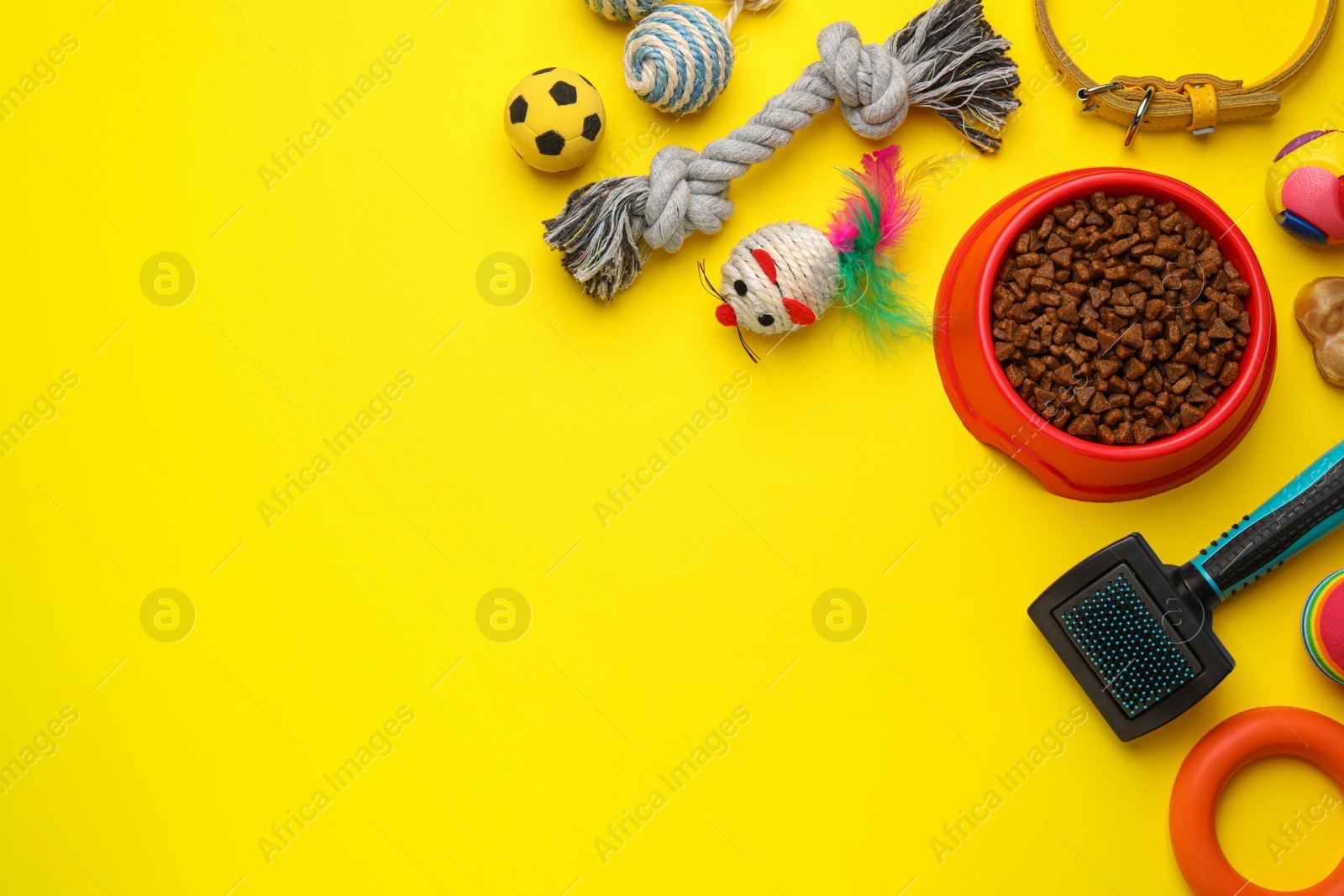 Photo of Flat lay composition with pet toys and feeding bowl on yellow background, space for text