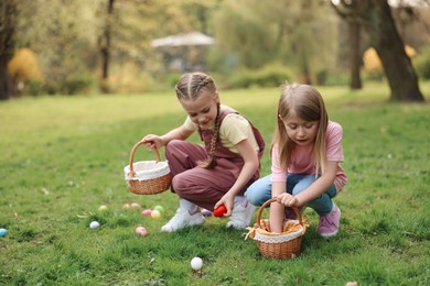 Photo of Easter celebration. Cute little girls hunting eggs outdoors