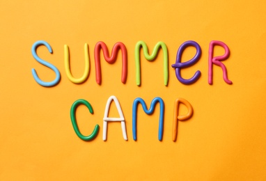 Photo of Text SUMMER CAMP made of modelling clay on color background, flat lay