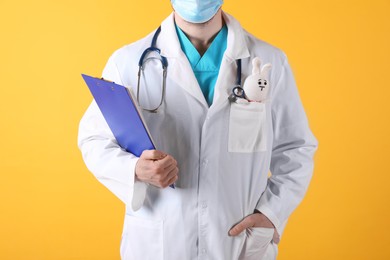 Photo of Pediatrician with toy bunny and stethoscope on yellow background, closeup