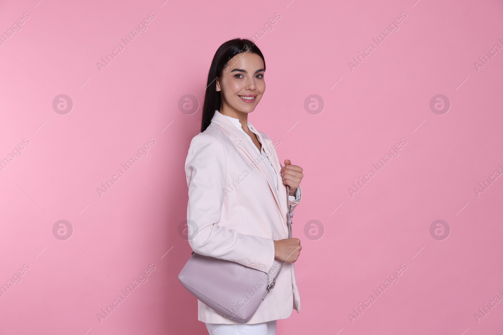 Photo of Beautiful young woman with stylish bag on pink background