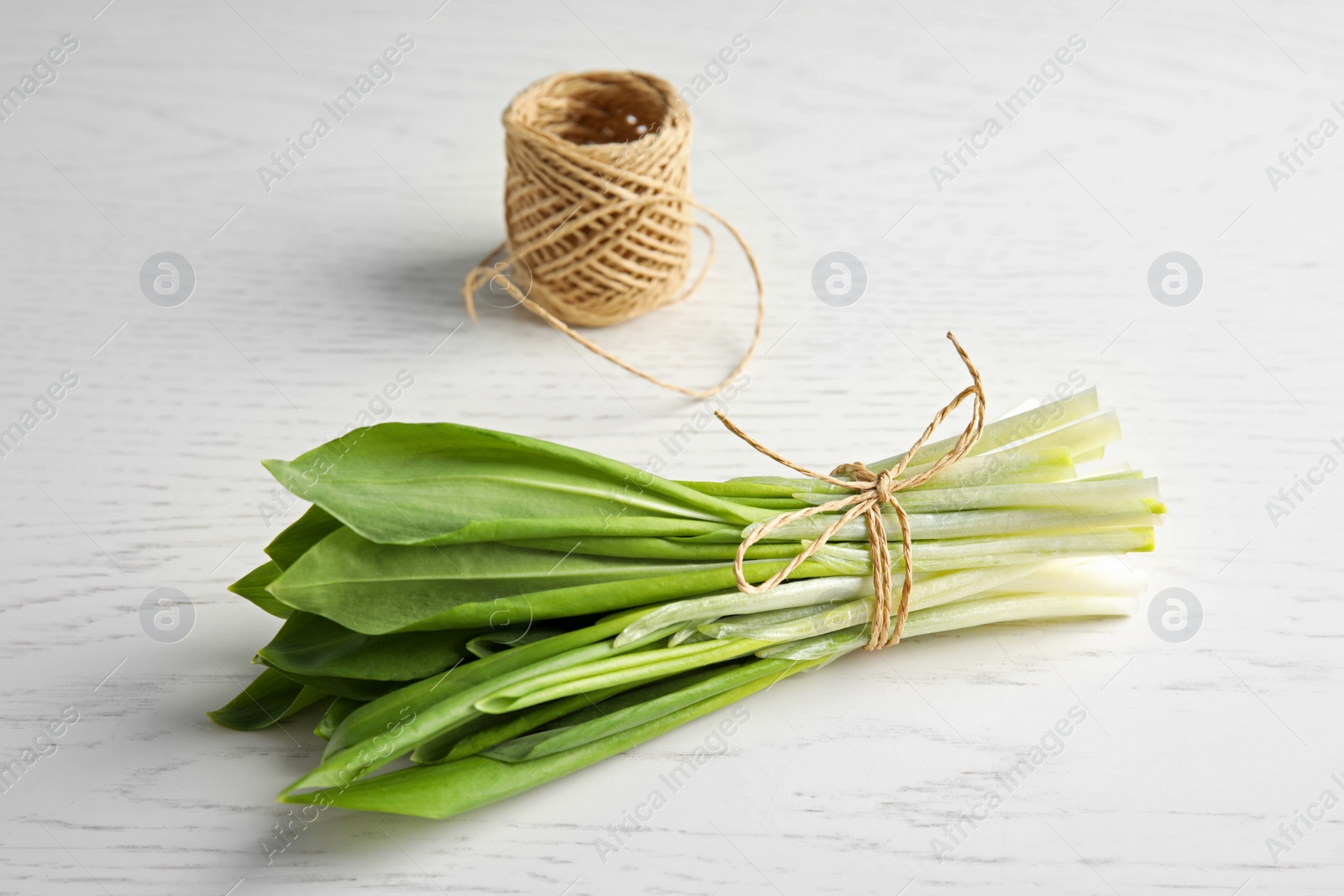 Photo of Bunch of wild garlic or ramson and thread on wooden table