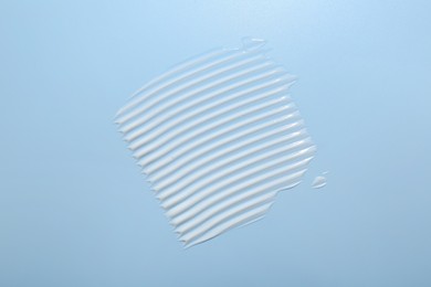 Photo of Samples of face cream on light blue background, top view