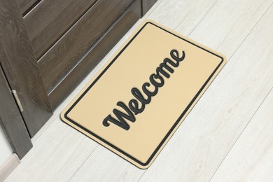 Photo of Beige doormat with word Welcome on white floor near entrance