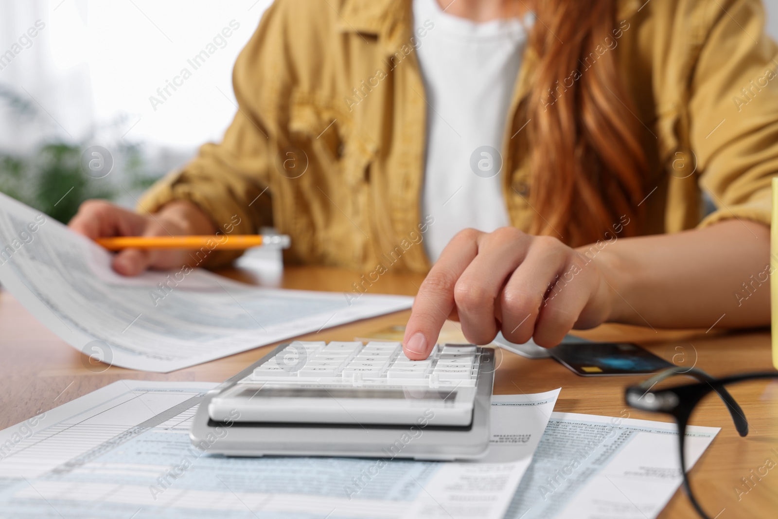 Photo of Woman calculating taxes at wooden table in room, closeup