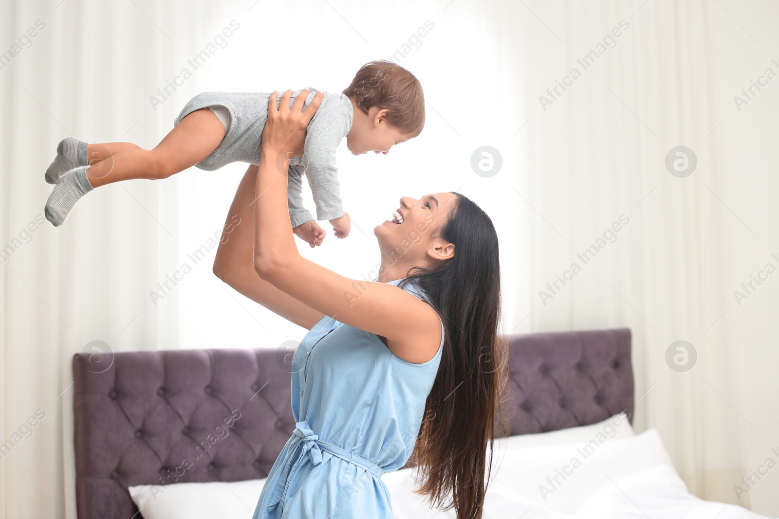 Photo of Young nanny playing with cute little baby in bedroom