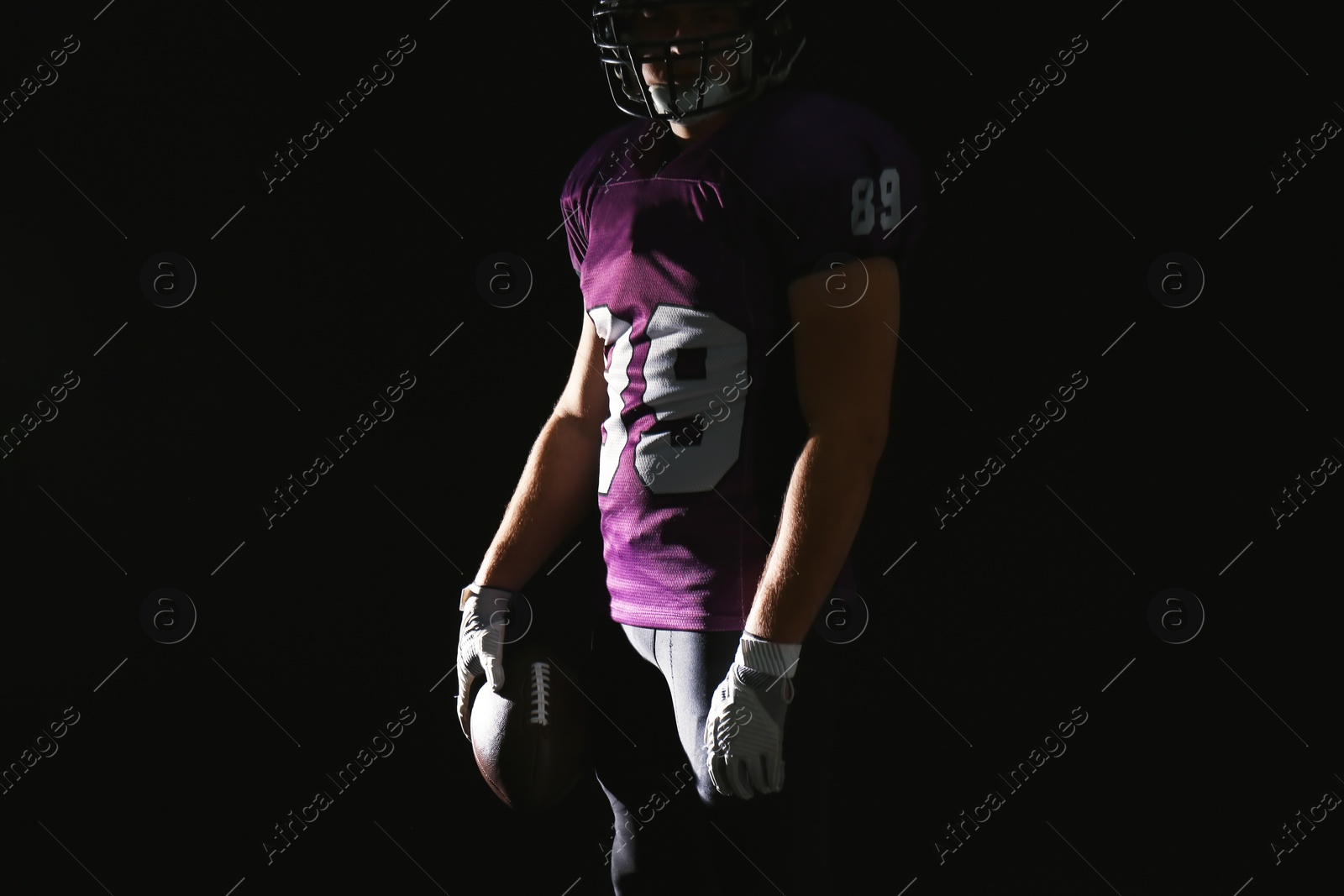 Photo of American football player with ball on dark background