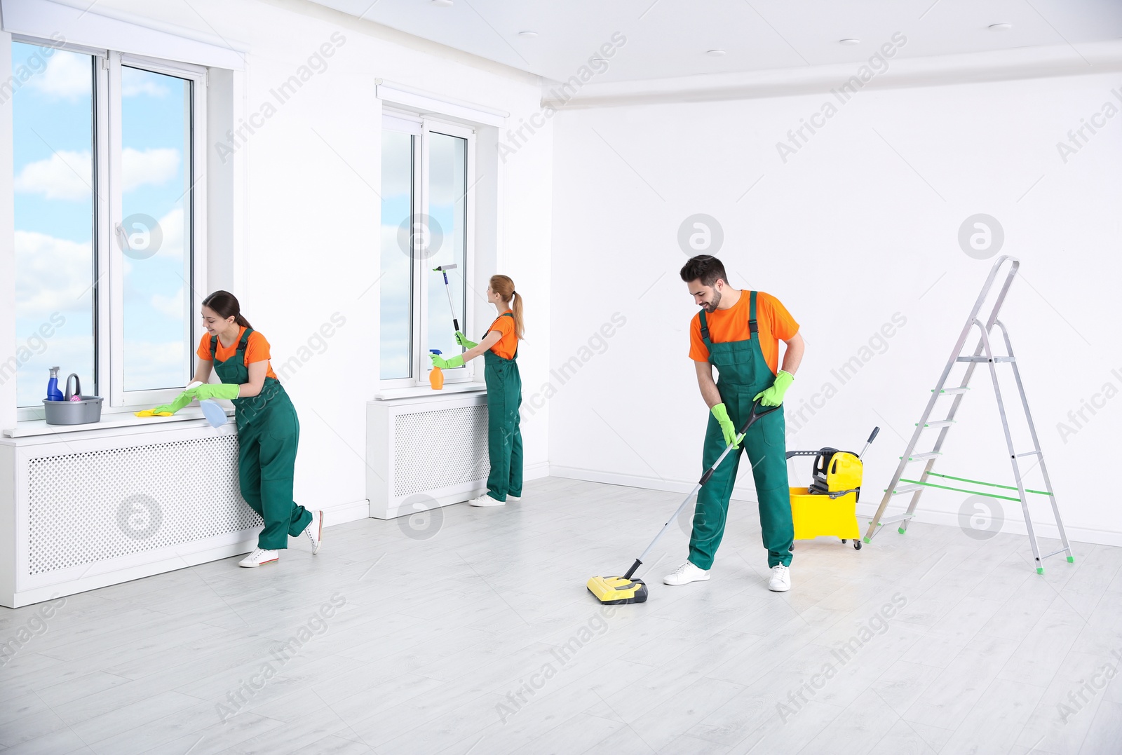 Photo of Team of professional janitors in uniforms cleaning room