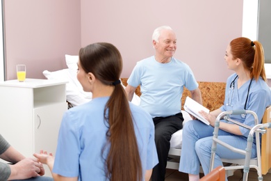 Nurses with senior patients in hospital ward. Medical assisting