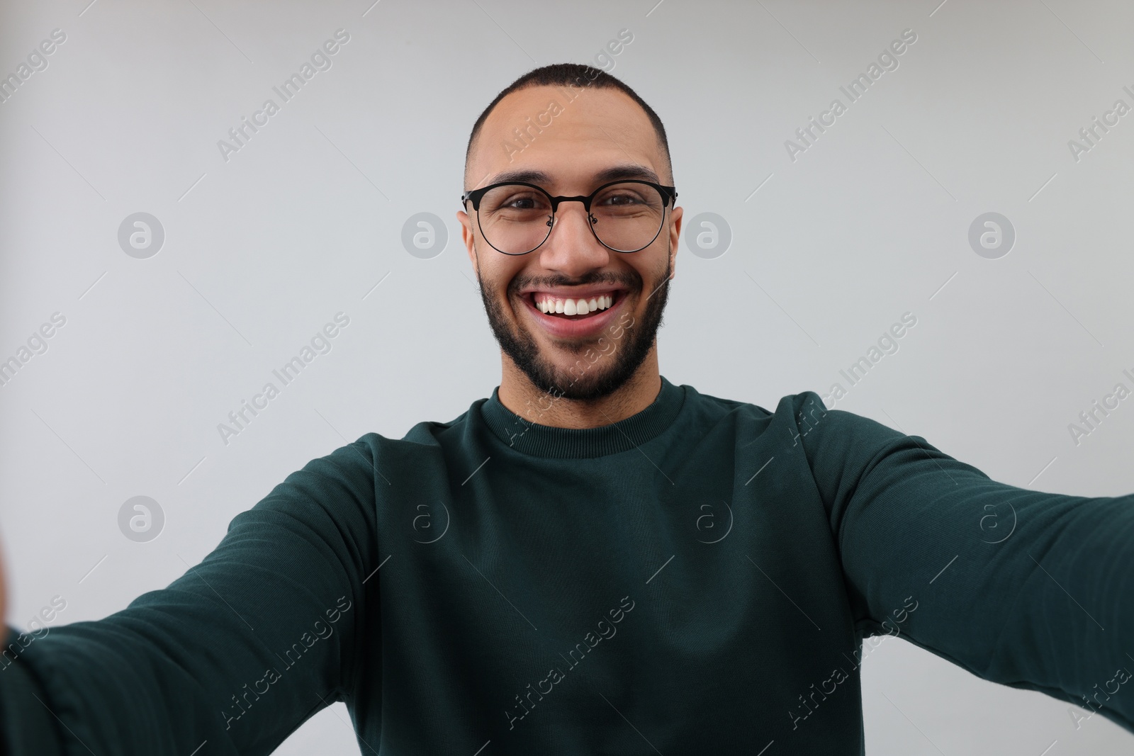 Photo of Smiling young man taking selfie on grey background