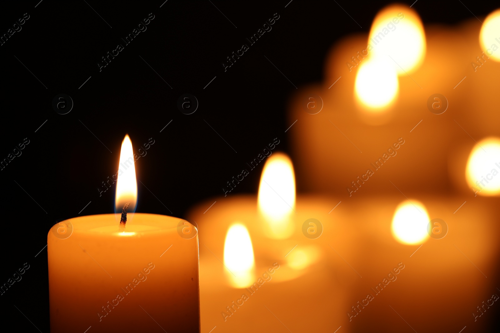 Photo of Burning candle on black background, closeup. Space for text