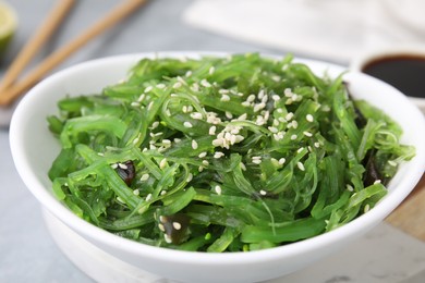 Photo of Tasty seaweed salad in bowl on table, closeup