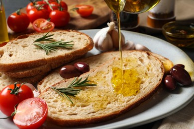 Photo of Pouring oil onto slice of bread on plate, closeup