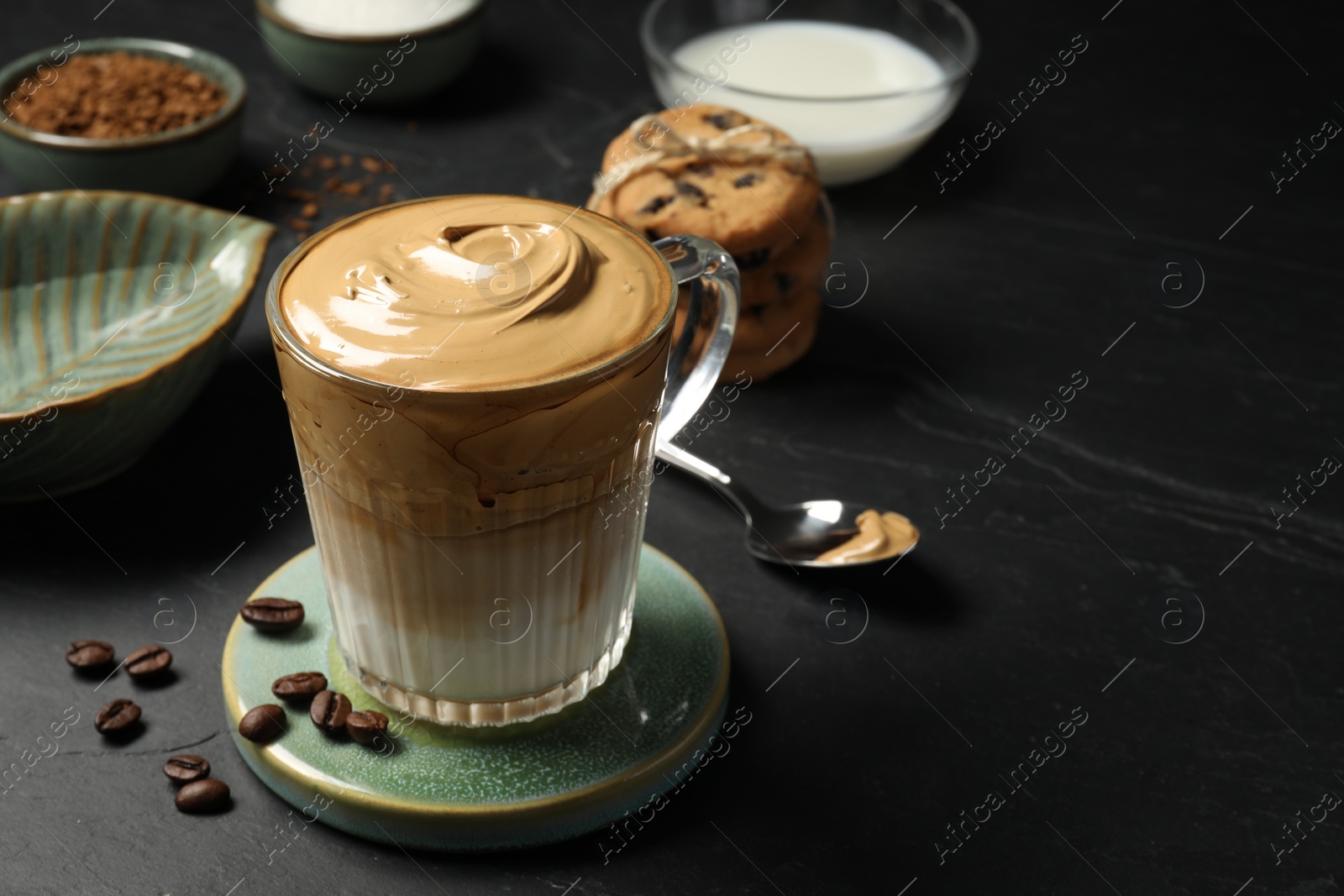 Photo of Glass mug of delicious dalgona coffee on dark table, space for text