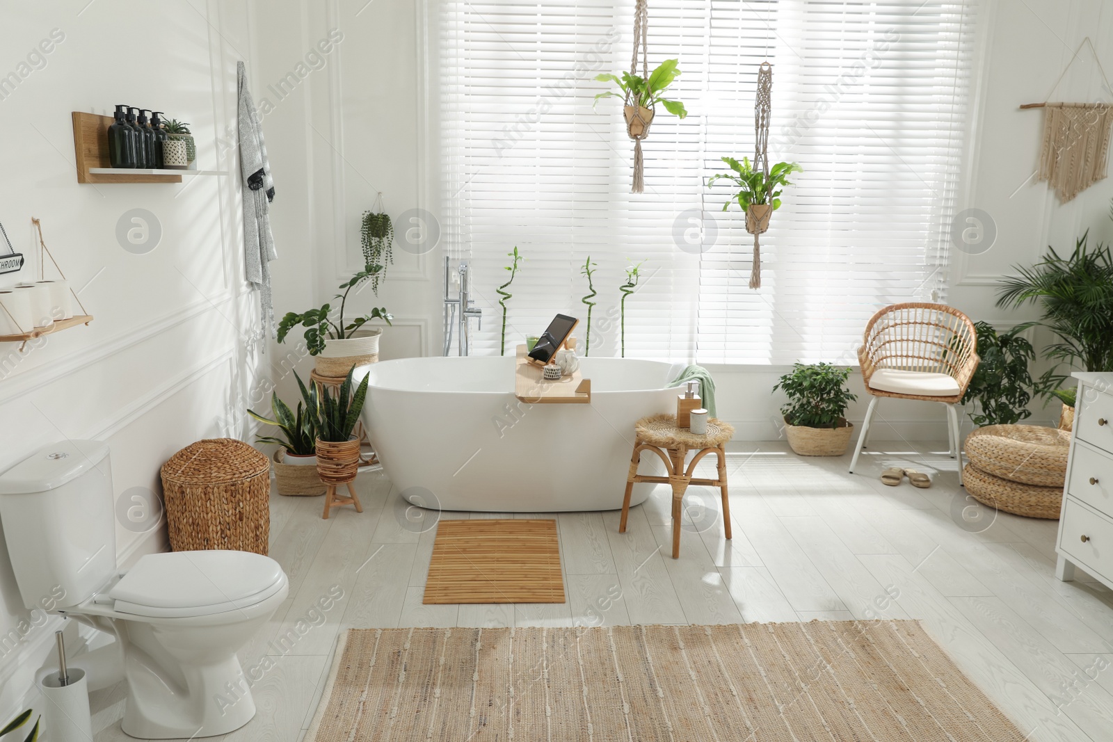 Photo of Stylish white tub and green houseplants in bathroom. Interior design