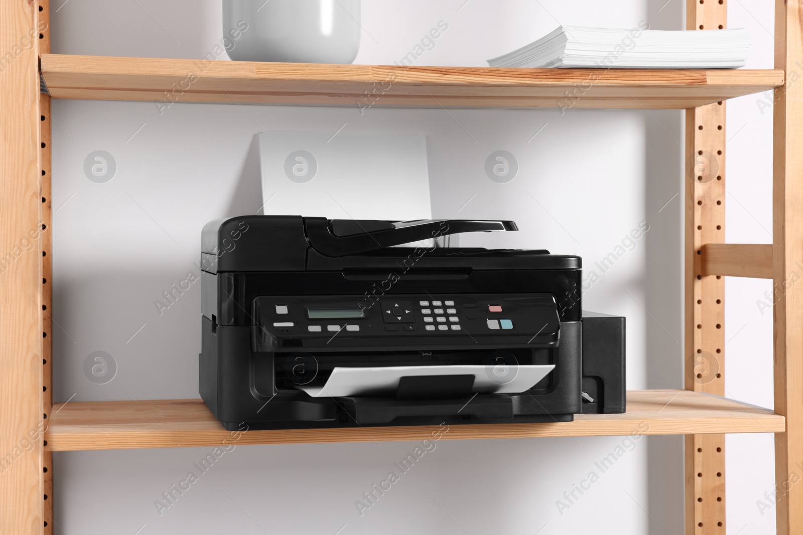 Photo of Modern printer with paper on wooden shelf in home office