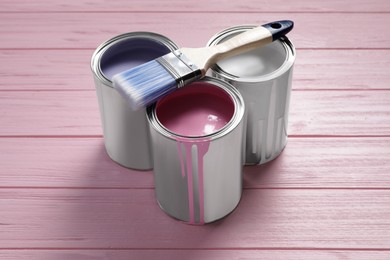 Photo of Canspastel paints and brush on pink wooden table