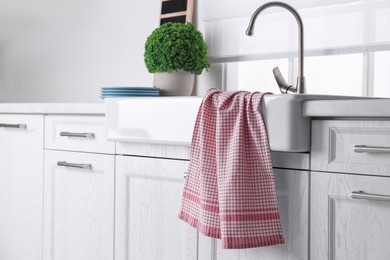 Photo of Clean checkered towel on sink in kitchen