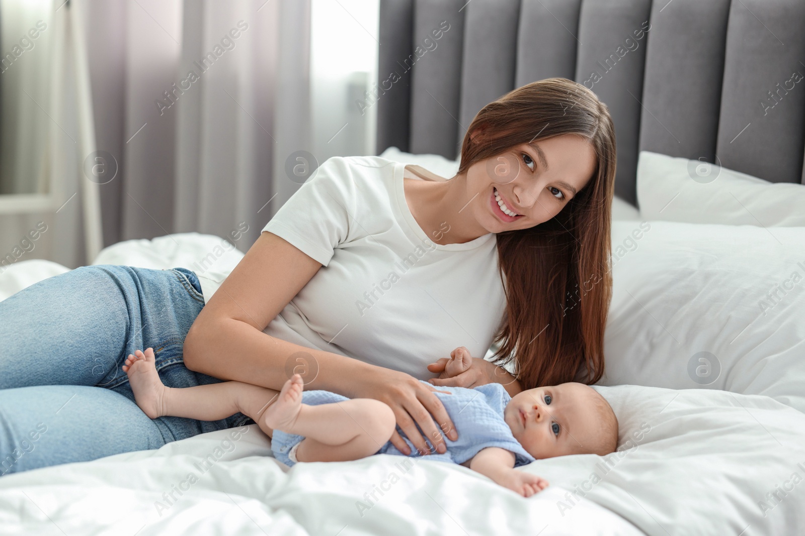 Photo of Mother with her cute baby on bed indoors