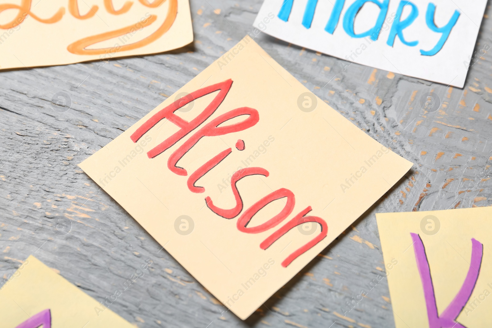 Photo of Paper sheet with baby name Alison on grey wooden table, closeup