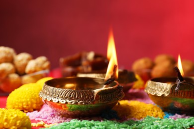 Photo of Happy Diwali. Diya lamps, colorful rangoli and flowers on table, closeup