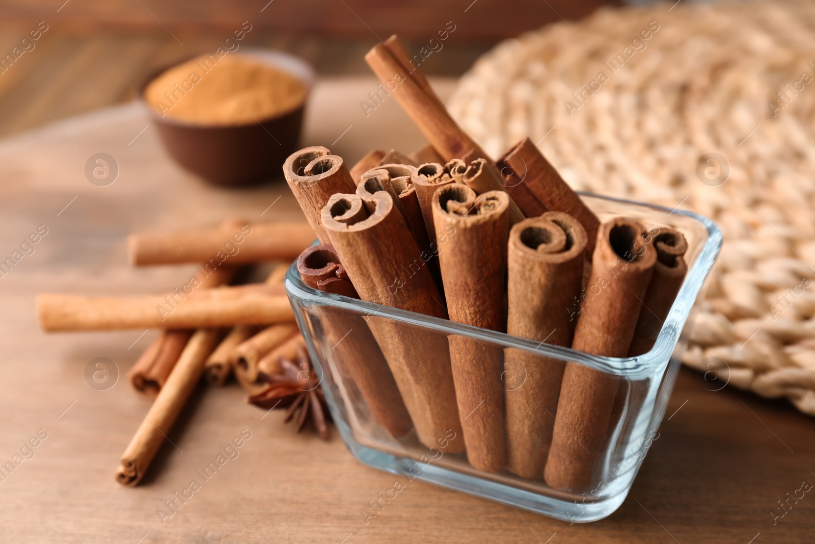 Photo of Bowl with aromatic cinnamon sticks on wooden table