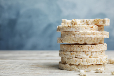 Stack of puffed rice cakes on white wooden table against light blue background. Space for text