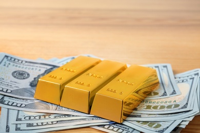 Photo of Gold bars and dollar bills on table. Space for text