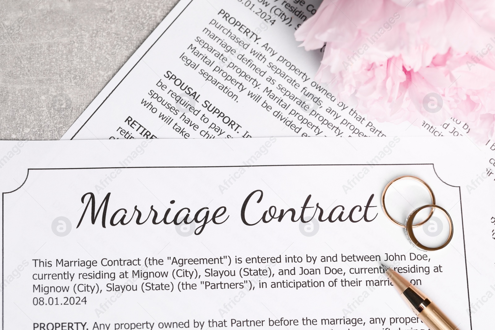 Photo of Marriage contract, wedding rings, pen and flowers on grey table, top view