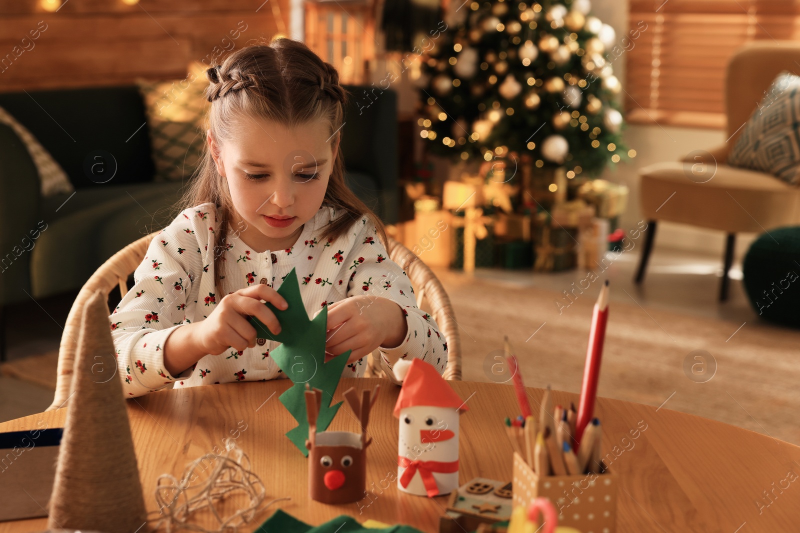 Photo of Cute child holding felt fir tree at home. Making Christmas decor