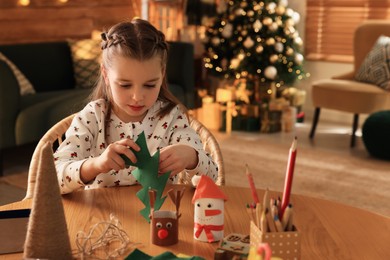 Cute child holding felt fir tree at home. Making Christmas decor