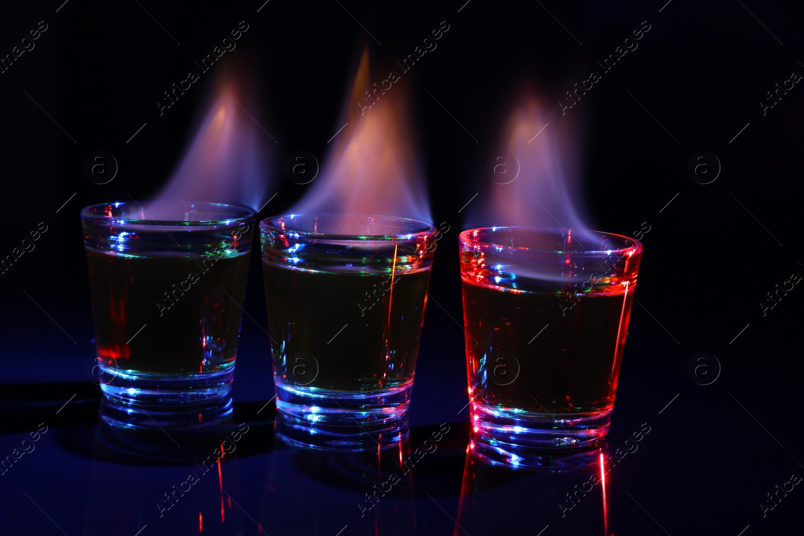 Photo of Flaming alcohol drink in shot glasses on dark background