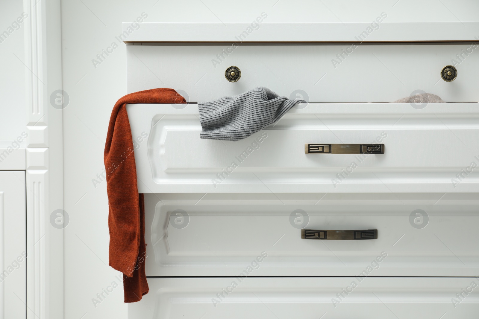 Photo of Cluttered chest of drawers indoors. Clothes in mess