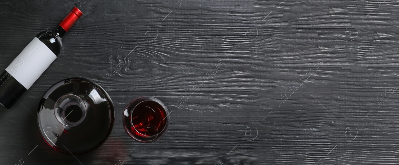 Image of Decanter, glass and bottle with red wine on wooden background, top view. Banner design