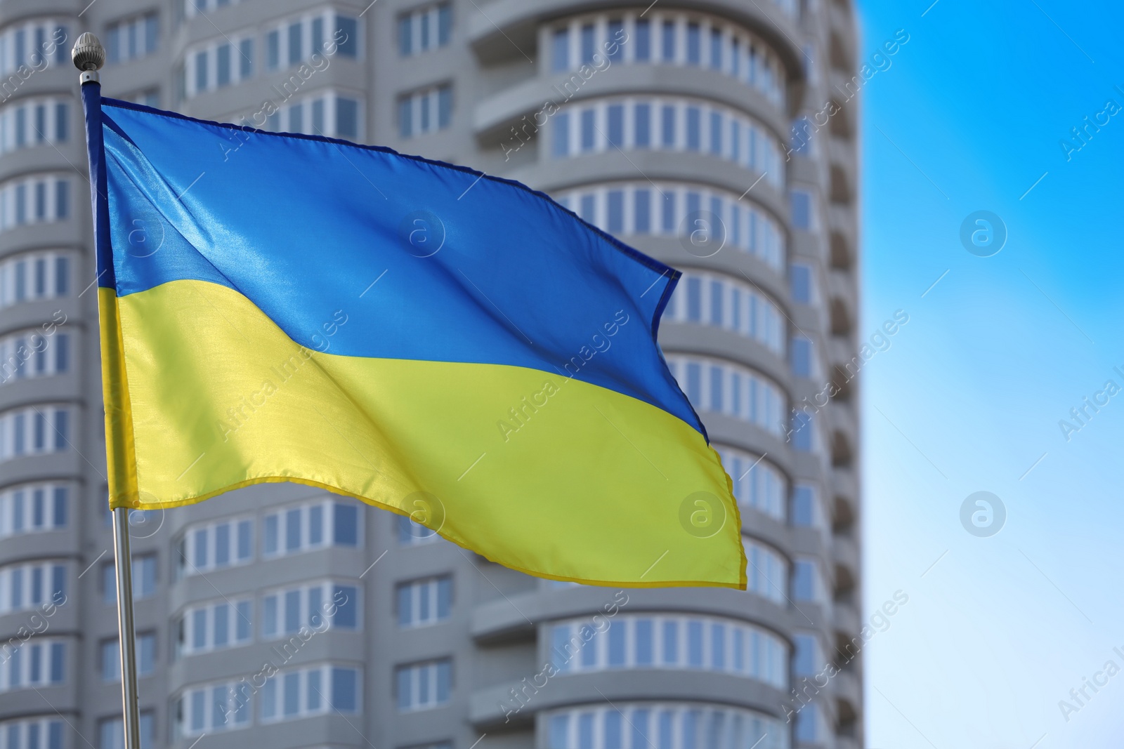 Photo of National flag of Ukraine fluttering near building on sunny day