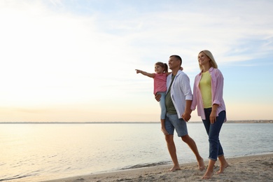 Photo of Happy parents with their child on beach, space for text. Spending time in nature
