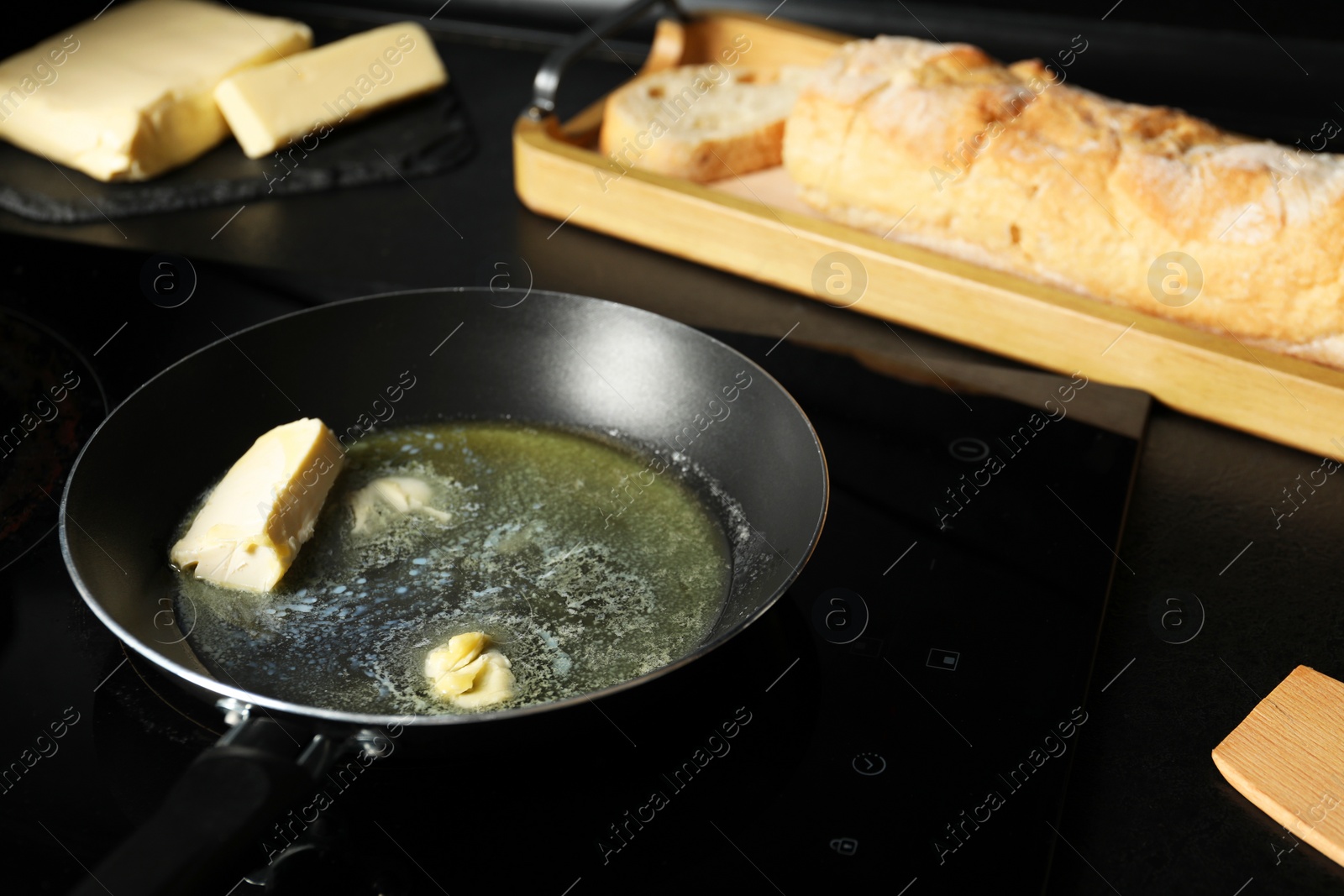 Photo of Melting butter in frying pan, dairy product and bread on black table