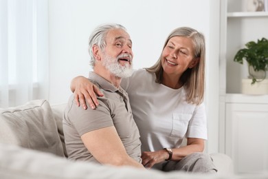 Photo of Happy senior couple relaxing on sofa at home