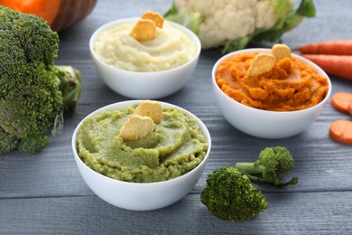 Bowls with different tasty puree and ingredients on light blue table