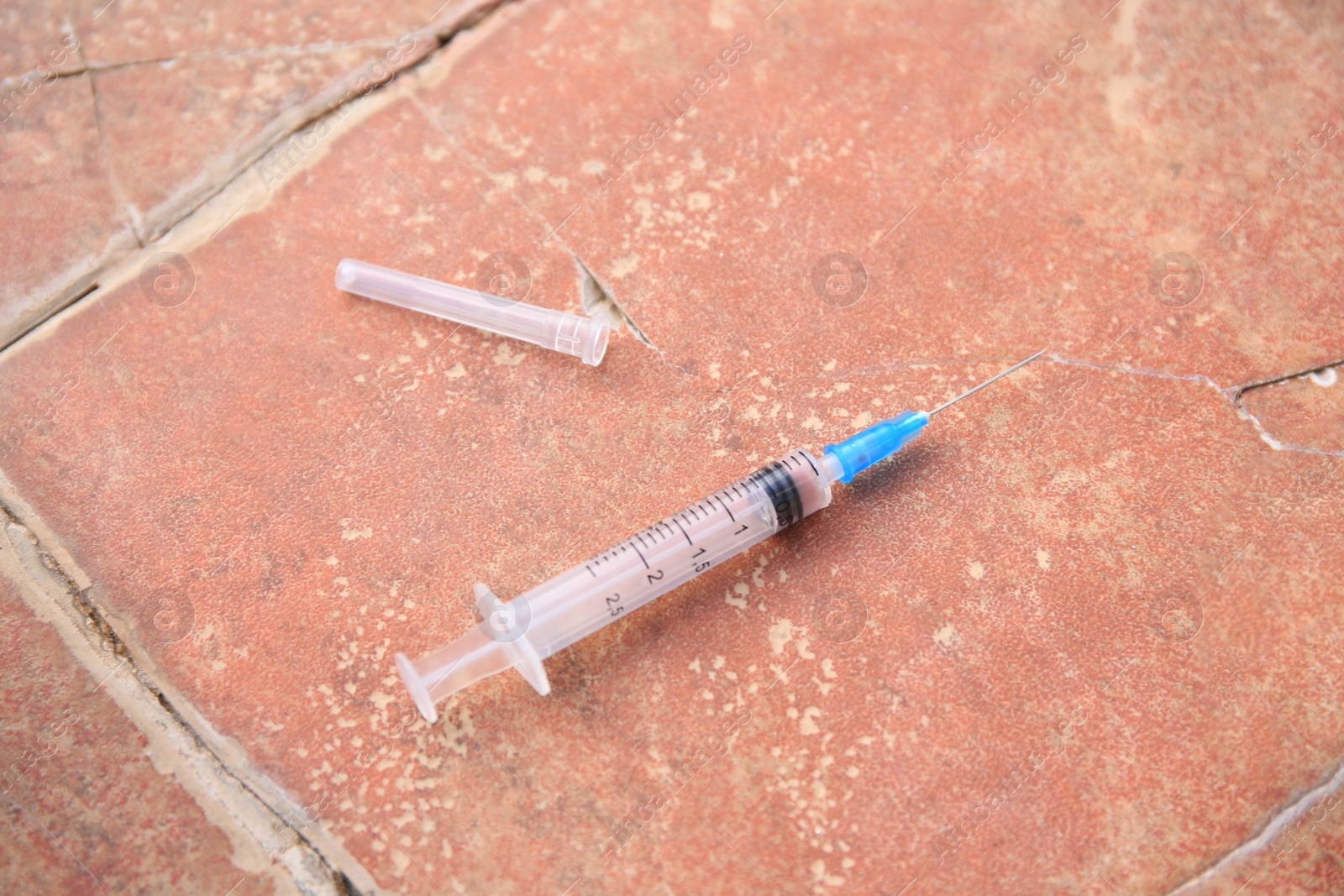 Photo of Disposable syringe with needle on red tiled surface