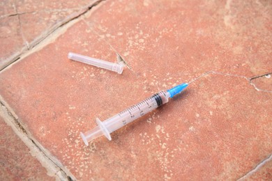 Disposable syringe with needle on red tiled surface