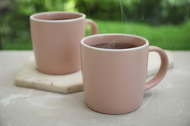 Photo of Cups of hot aromatic coffee on white windowsill, closeup. Rainy weather