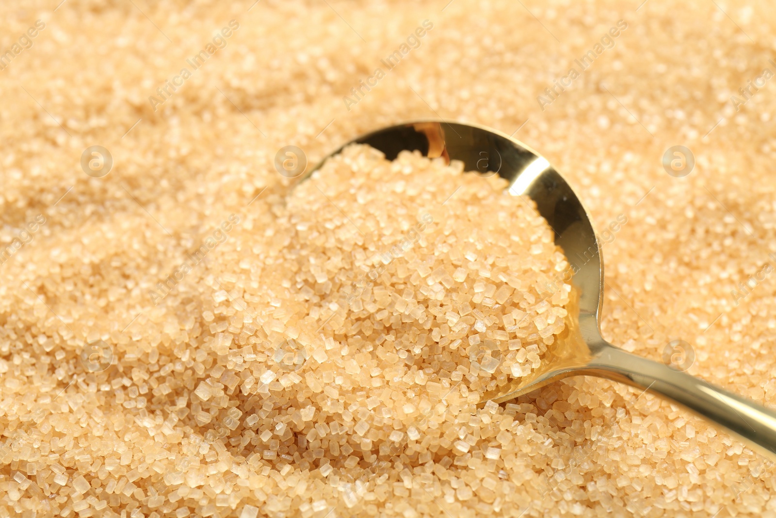 Photo of Spoon on granulated brown sugar, closeup view