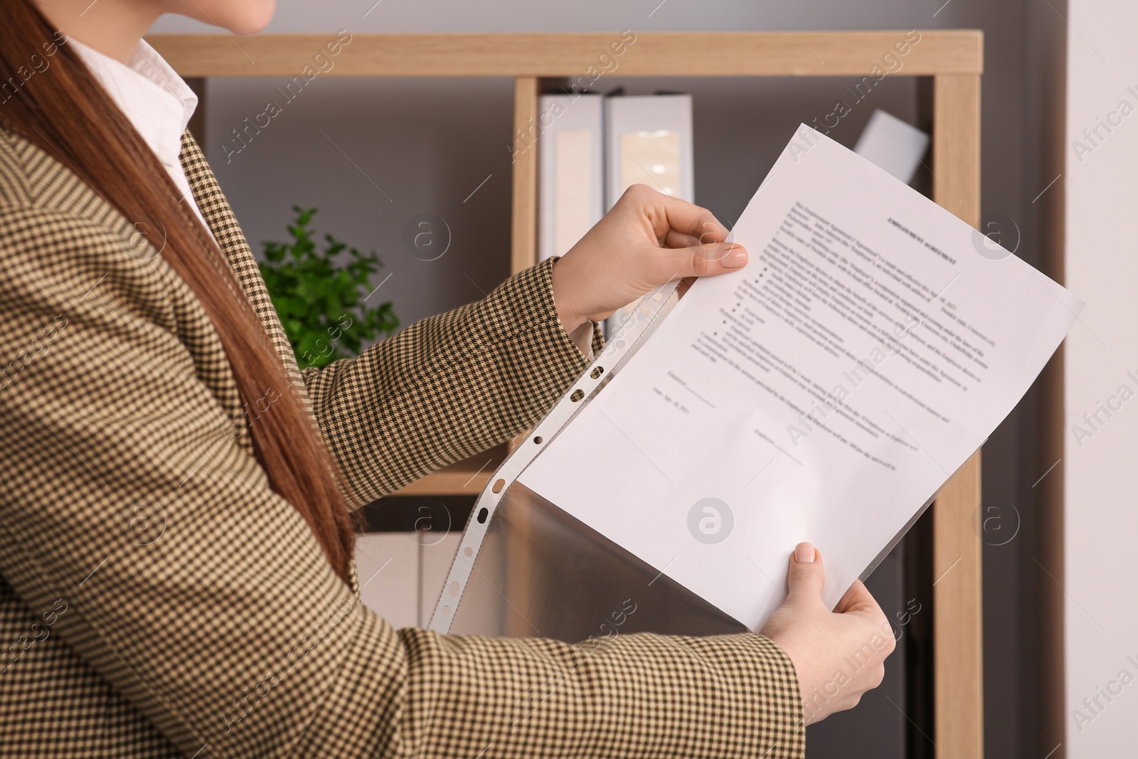 Photo of Businesswoman putting document into punched pocket in office, closeup