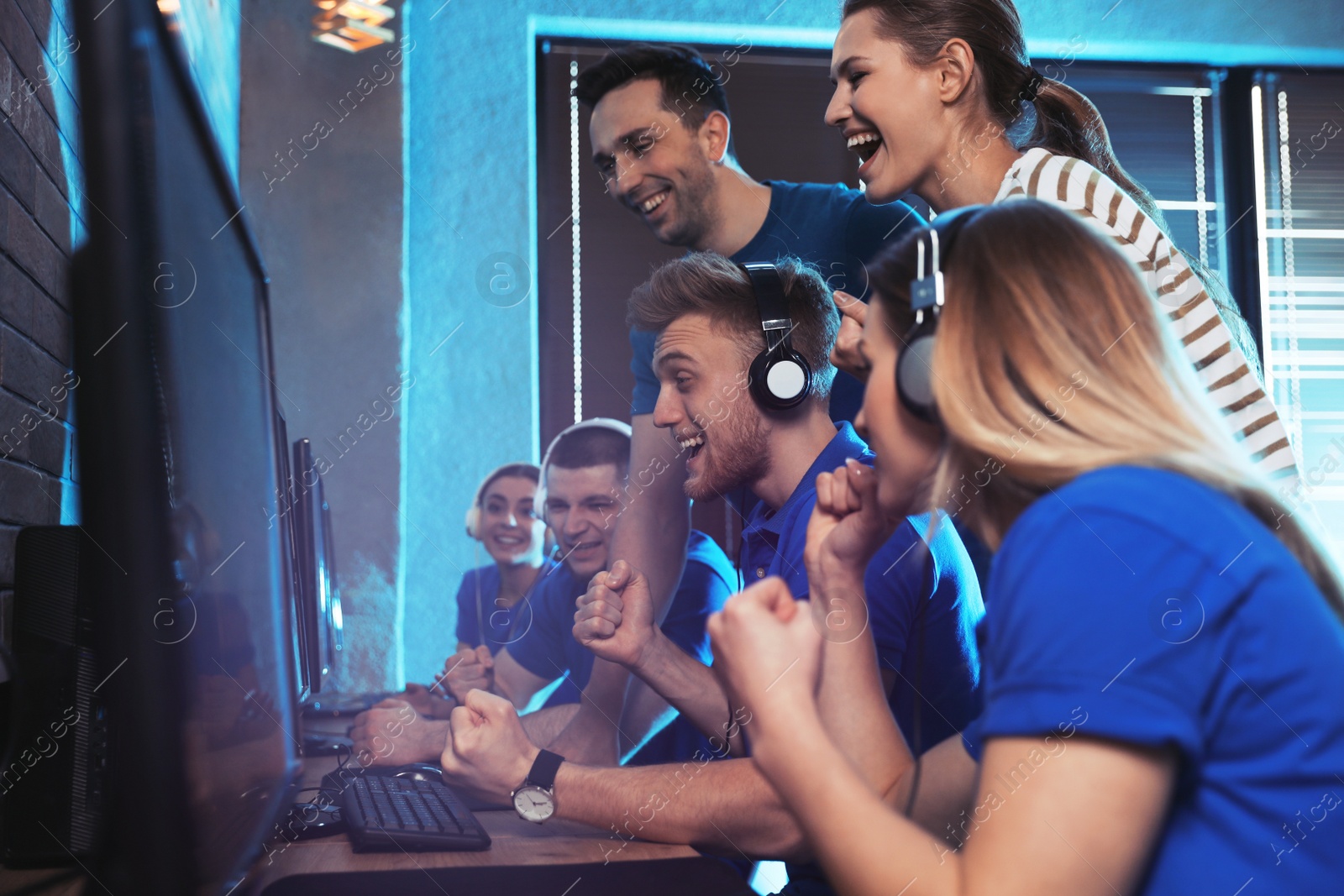 Photo of Group of people playing video games in internet cafe