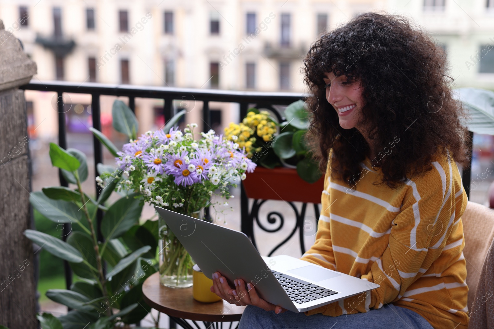 Photo of Beautiful young woman using laptop on balcony with green houseplants. Space for text