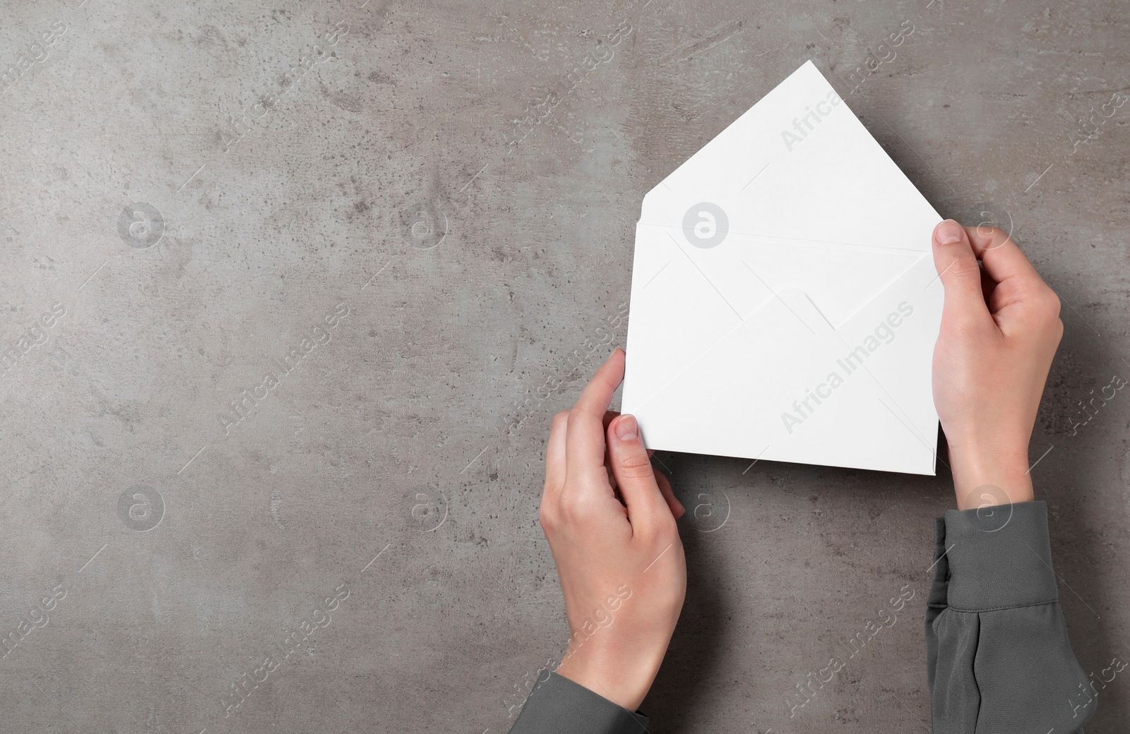 Photo of Woman with letter envelope at grey textured table, top view. Space for text