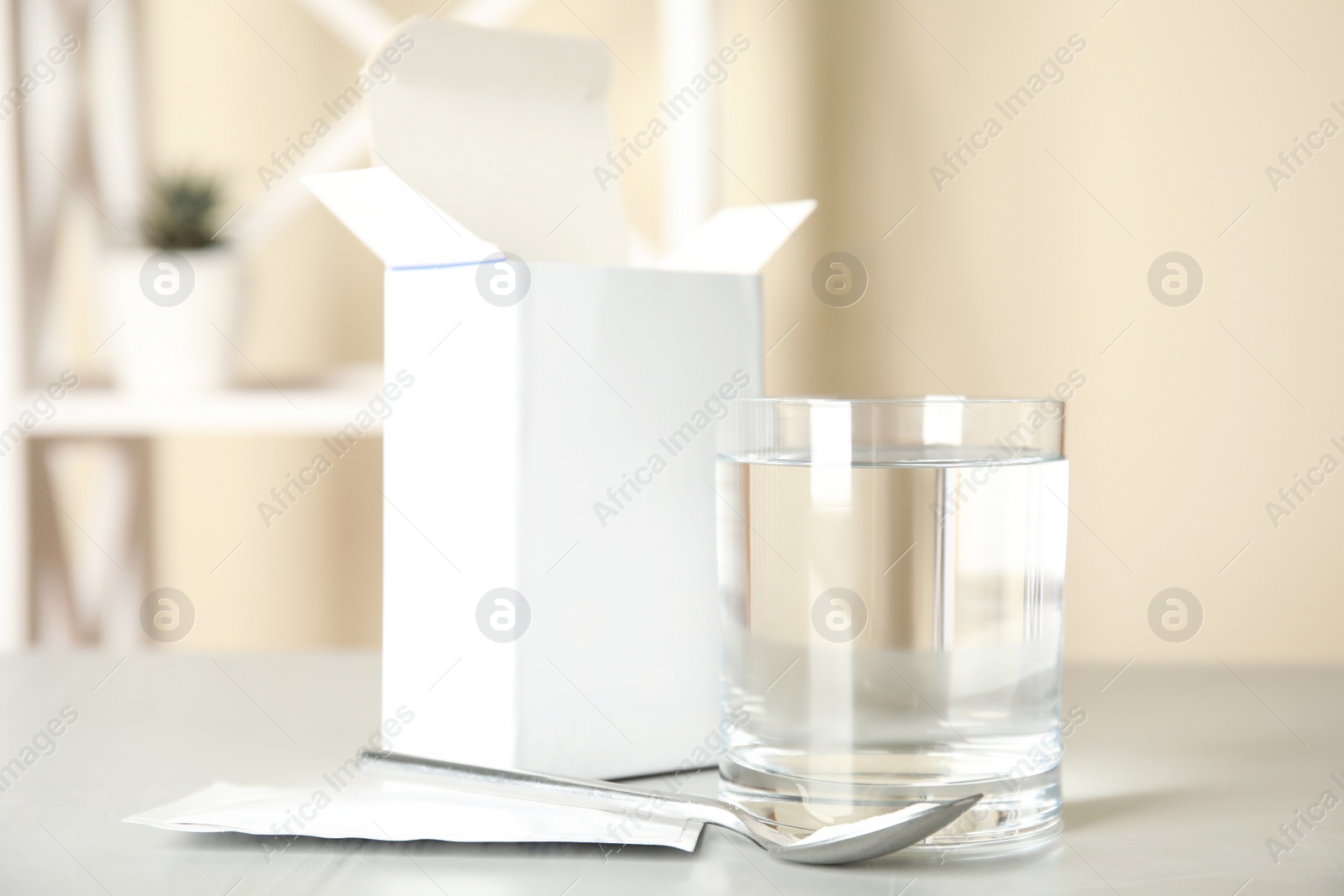 Photo of Medicine sachet, glass of water and spoon on light table