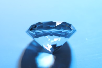 Photo of Beautiful dazzling diamond on blue background, closeup