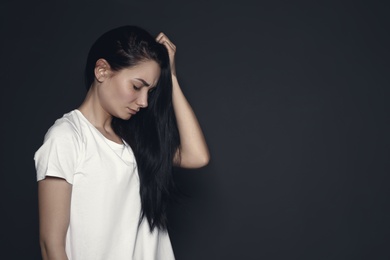 Photo of Portrait of upset young woman on dark background. Space for text